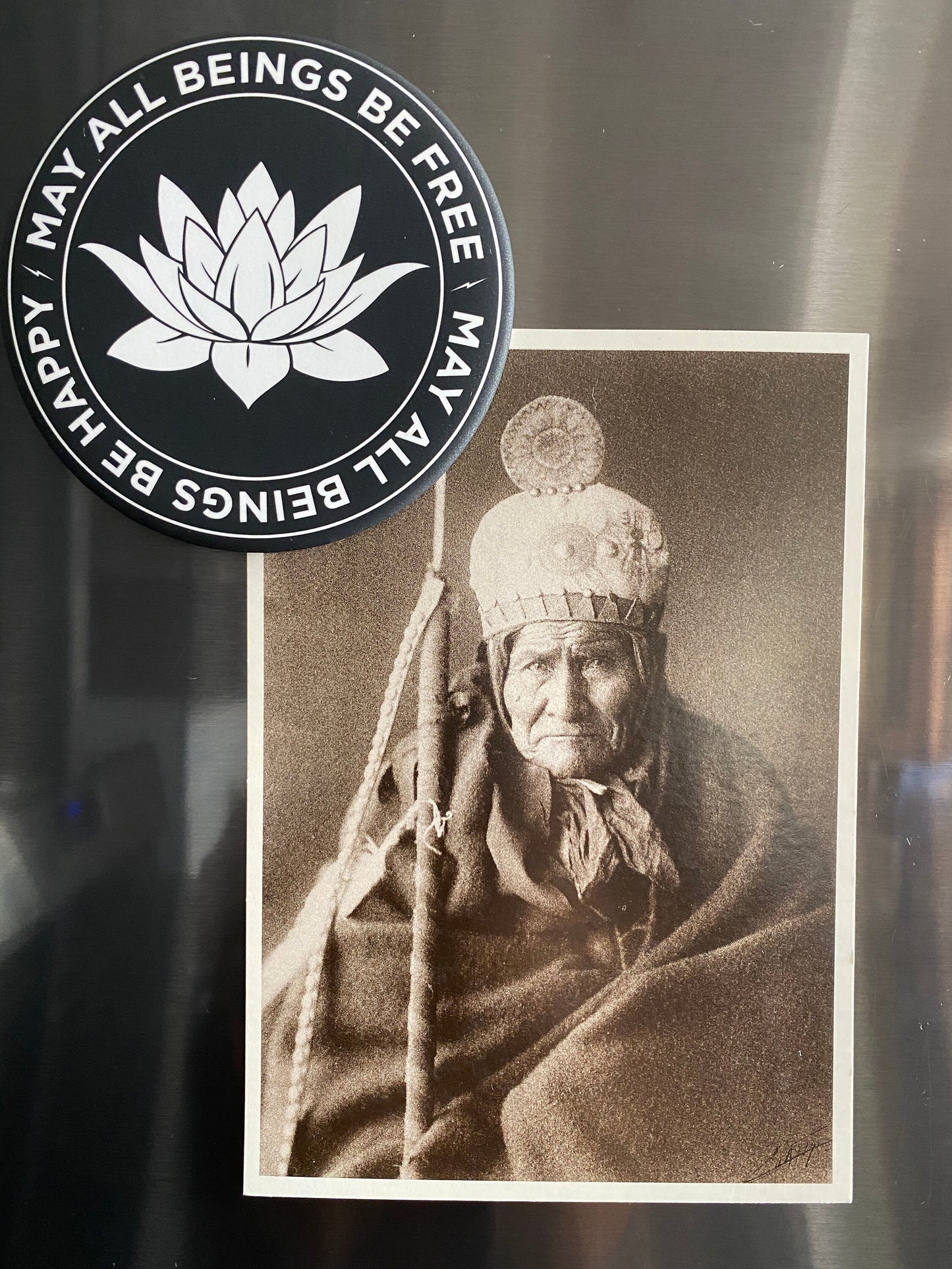 Vintage photograph of Geronimo being held onto a refrigerator with a 3.5" round black and white magnet with lotus flower design and text, may all beings be free, may all beings be happy.