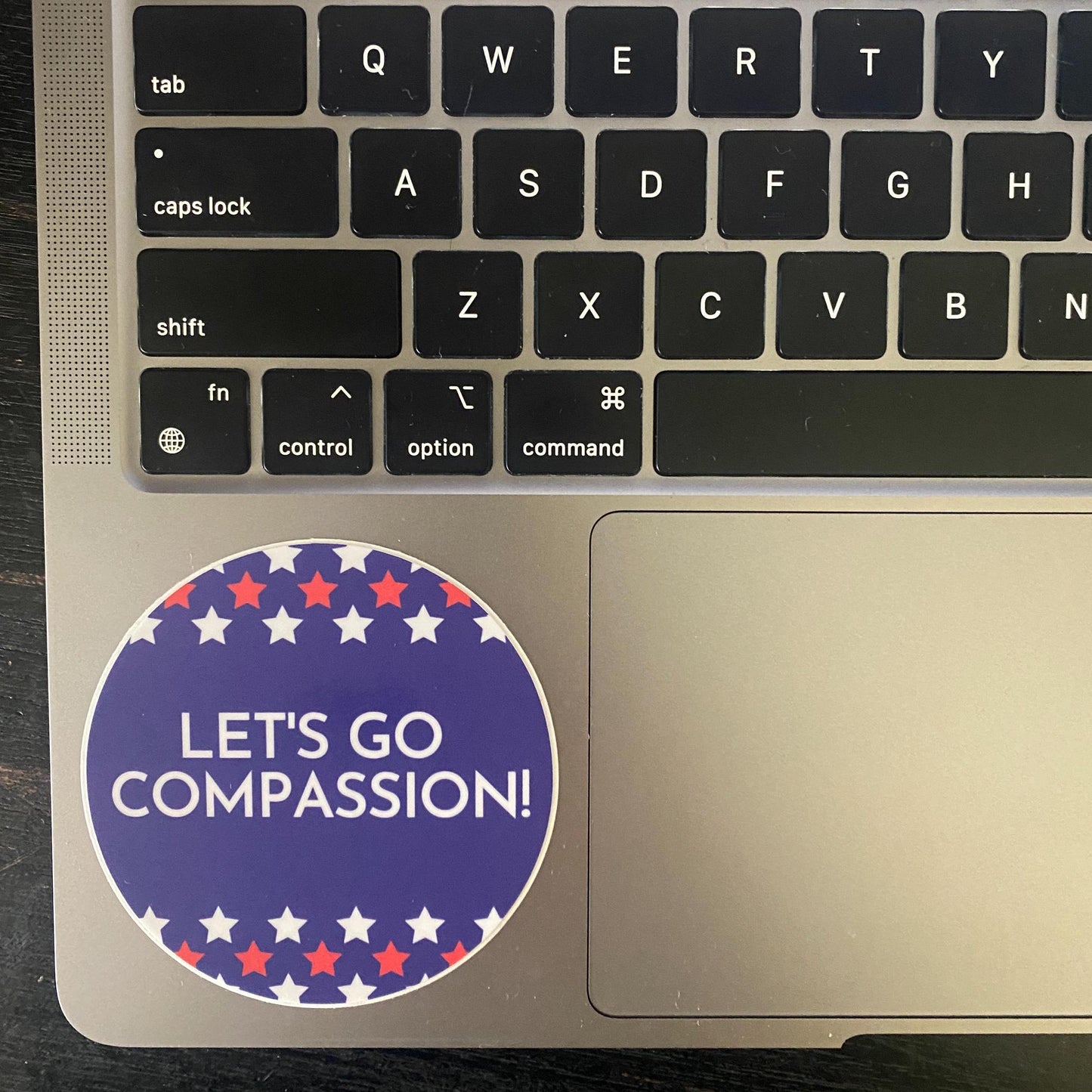 Laptop with a 'Let's Go Compassion!' sticker on the palm rest area