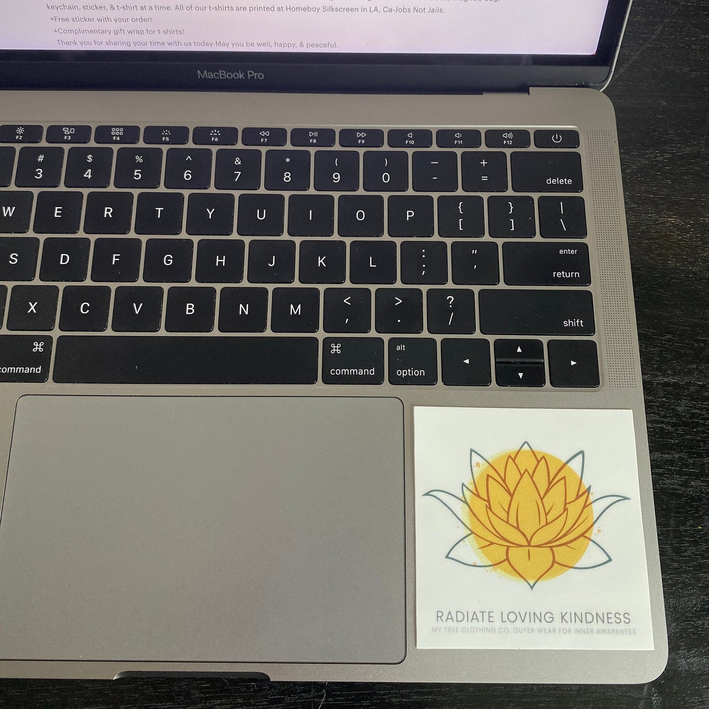 Laptop with a sticker of a yellow flower 'Radiate Loving Kindness' 3" square sticker.