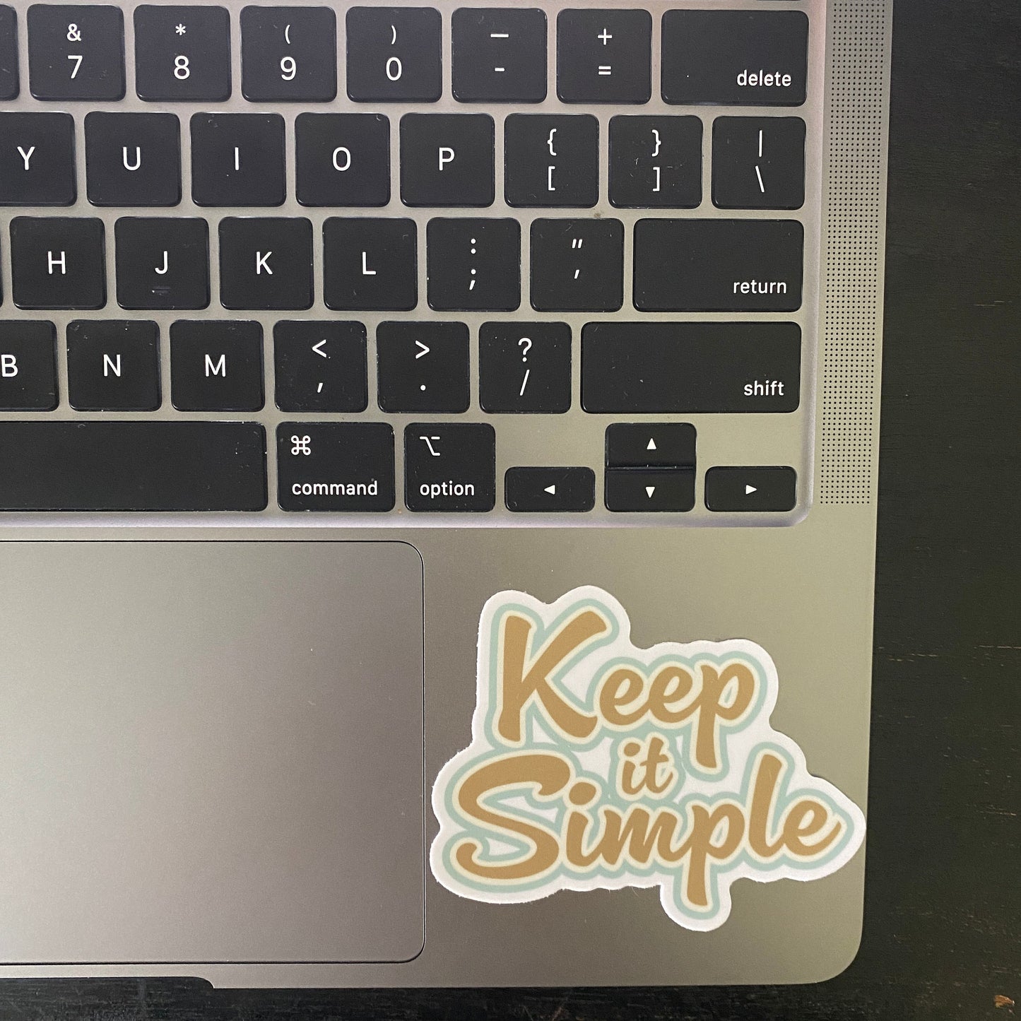 12 Step recovery slogan sticker in gold and blue with the text, 'Keep it Simple' attached to a laptop.