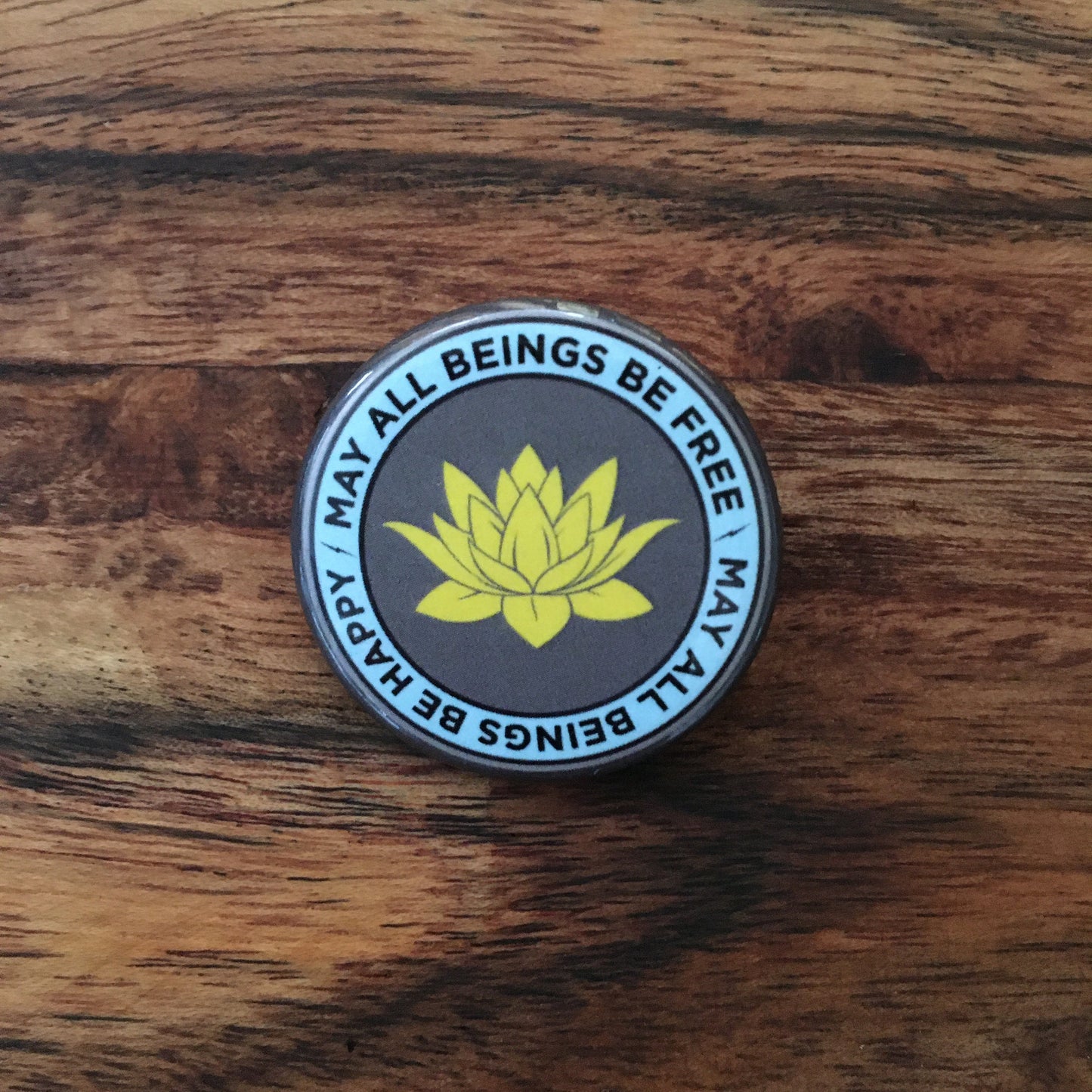 Round badge with lotus flower and text on a wooden surface