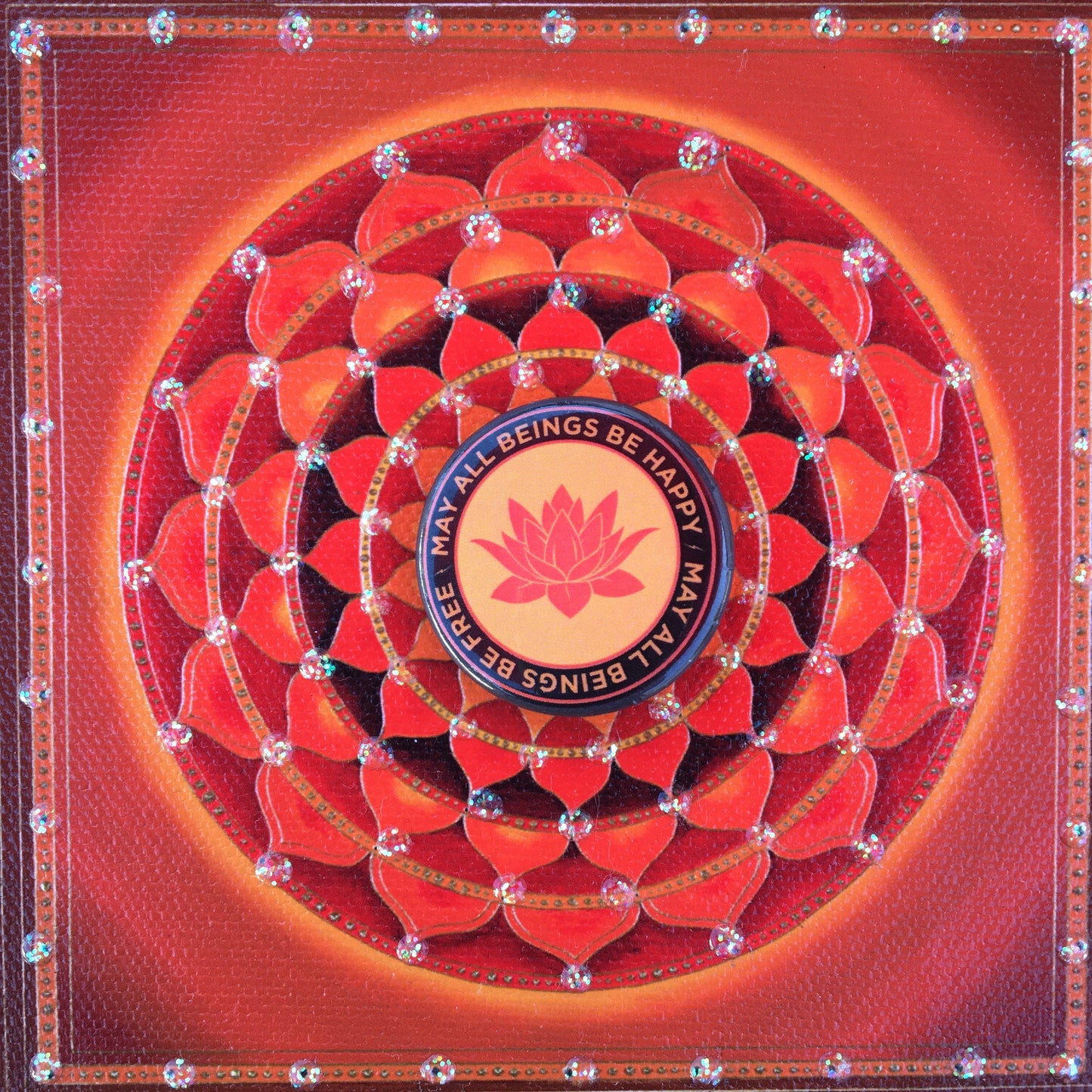1.25" Orange round pin back button with a buddhist lotus flower and the text 'may all beings be happy may all beings be free' with red mandala design.