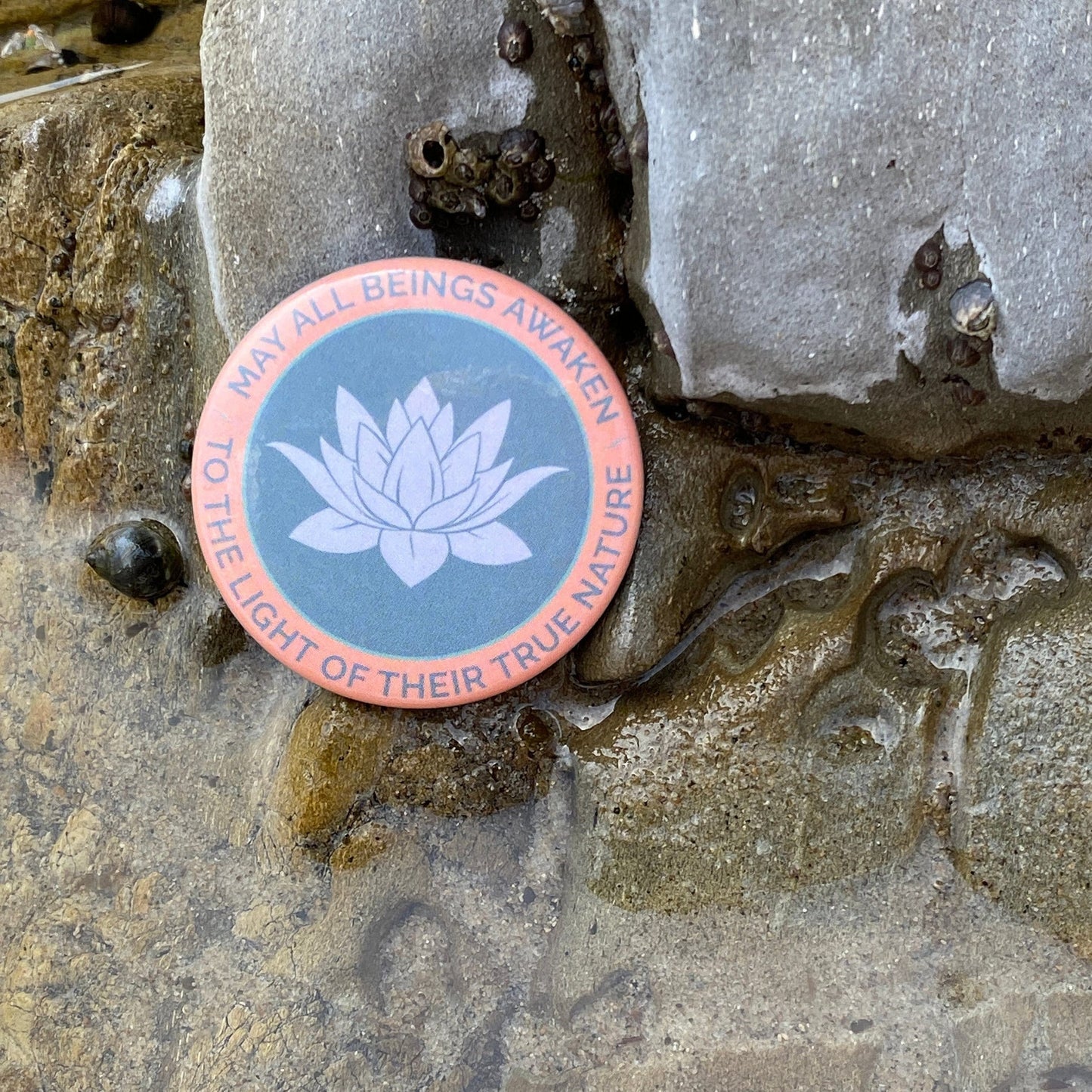 Round sticker with lotus flower design and text on a textured stone surface