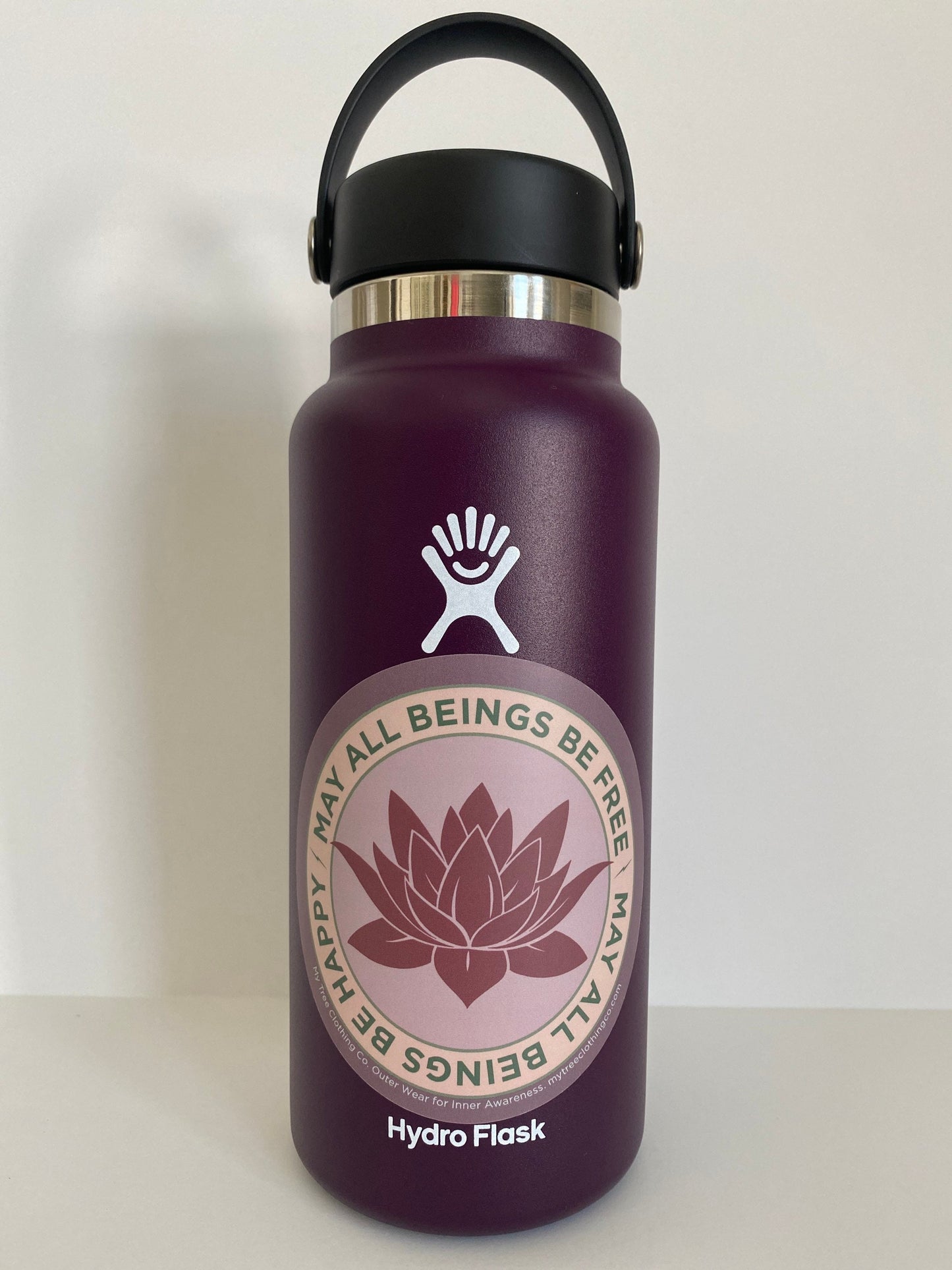 Purple Hydro Flask water bottle with a 4" Circular sticker with lotus flower design and the text, MAY ALL BEINGS BE FREE MAY ALL BEINGS BE HAPPY.
