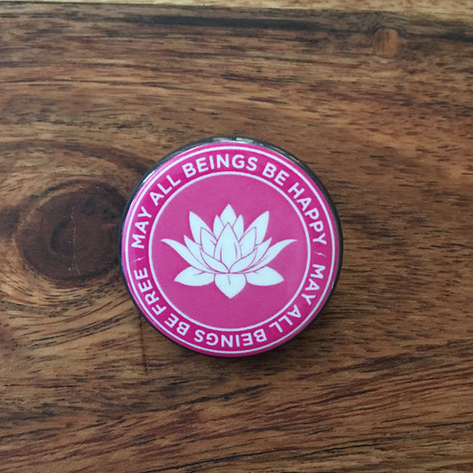Pink button with white lotus flower and text on a wooden surface