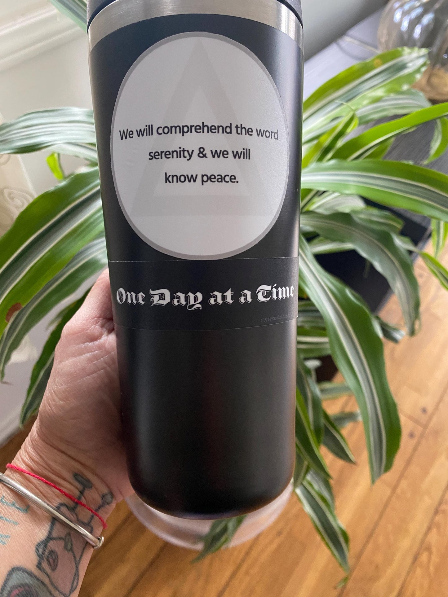 Black tumbler with black and white, old english font 'One Day at a Time' sticker.