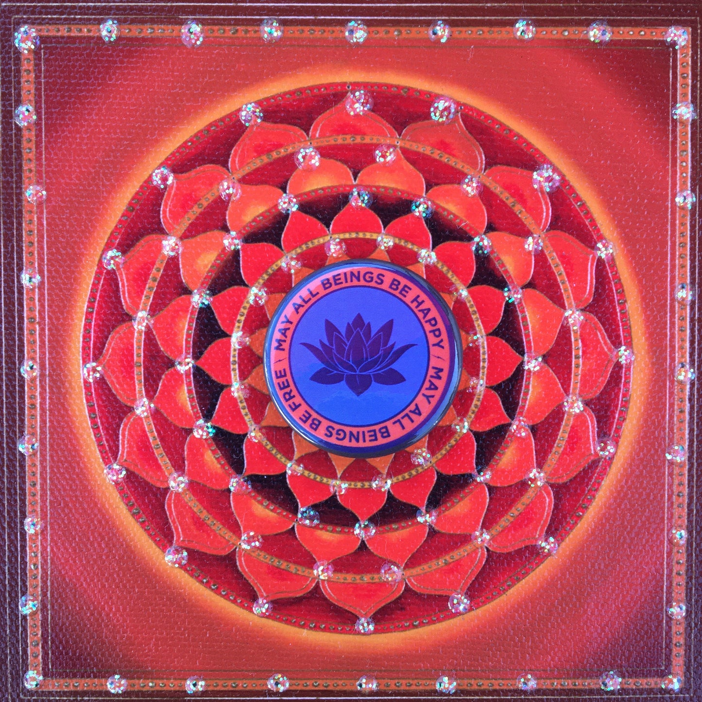 Red and blue Buddhist pin back button 1.25" circular with a lotus flower design and text, may all beings be free may all beings be happy.