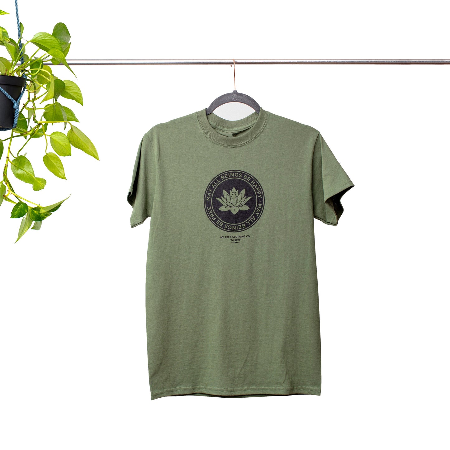 Green Buddhist lotus shirt with the text, May All Beings Be Happy May All Beings Be Free, on a hanger against a white background.