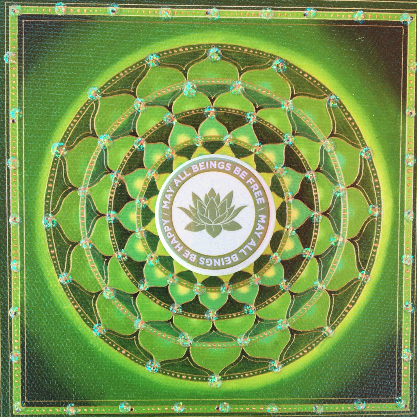Decorative green mandala with a light green 1.25" circular Buddhist pin back button with text and a lotus symbol.