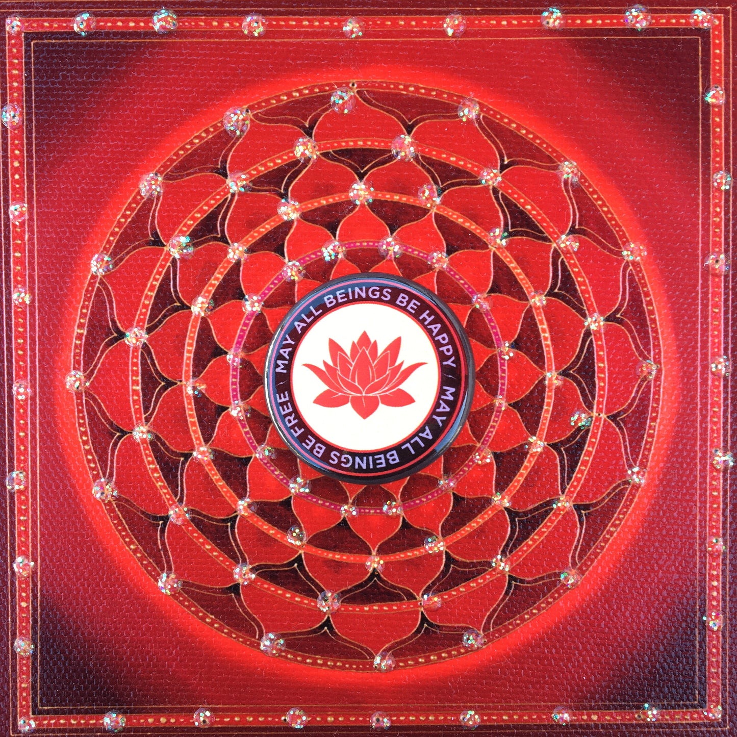 Decorative red mandala with a 1.25" pin back button with a red lotus flower design and the text, may all beings be free may all beings be happy.