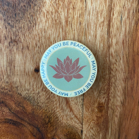 Round button with lotus flower design Text on button from metta prayer, may you be peaceful may you be free may you be happy.