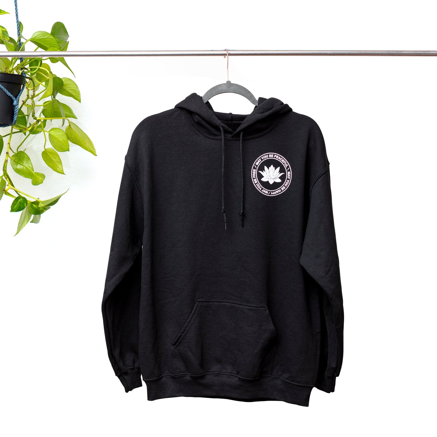 Black hoodie with a white lotus and the mettā prayer, 'may you be peaceful may you be happy may you be free.'