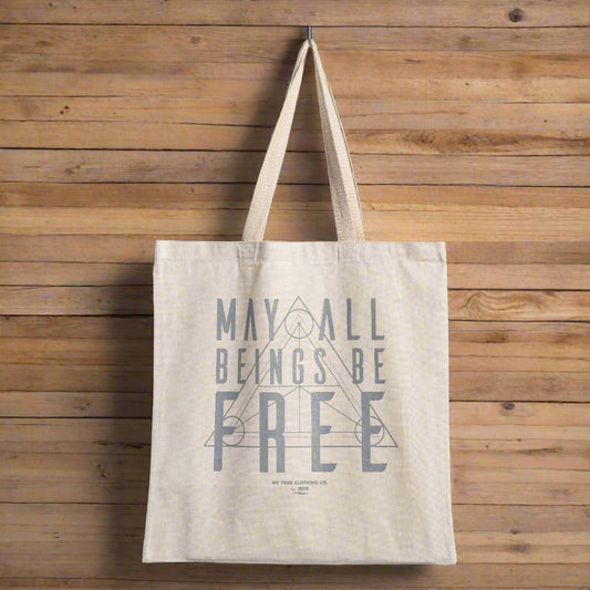 Beige tote bag with text, may all beings be free with a sacred geometry design.