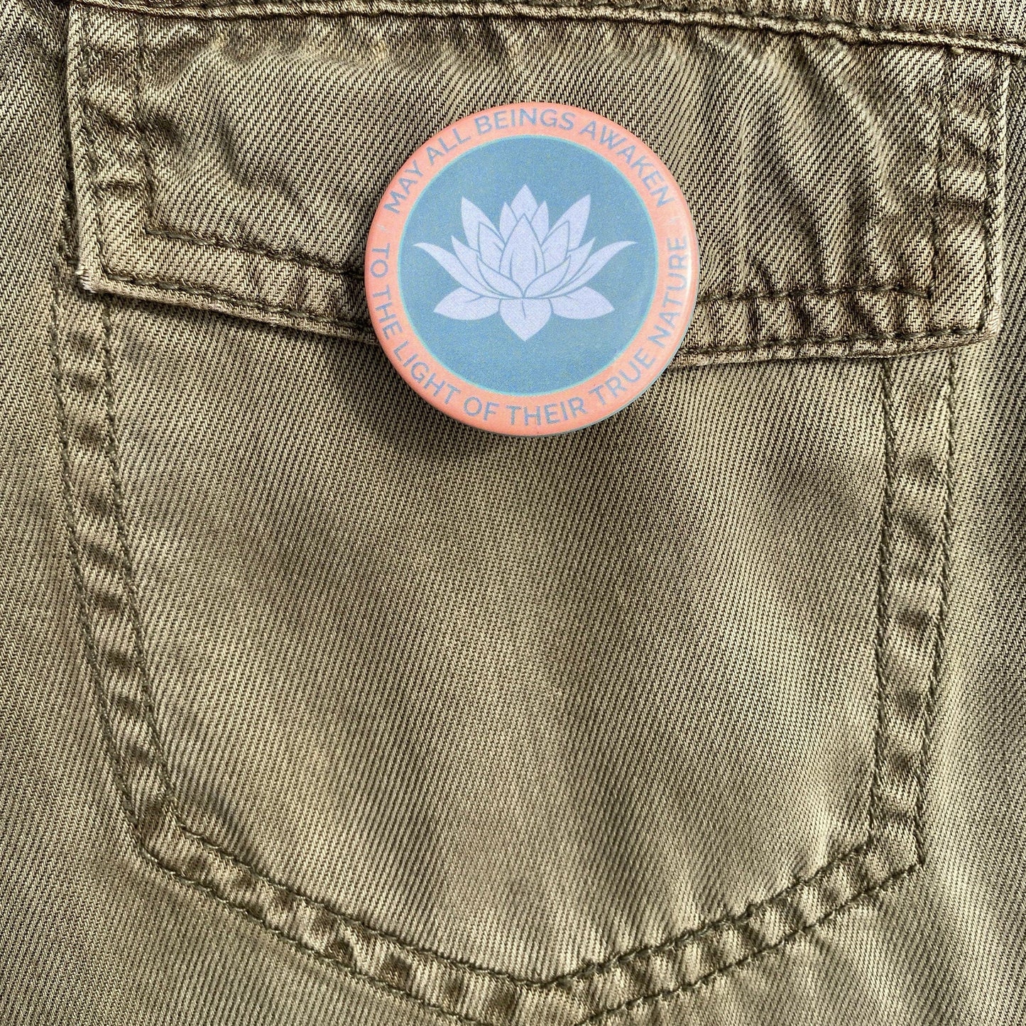 Pin with a lotus flower design on a green pocket