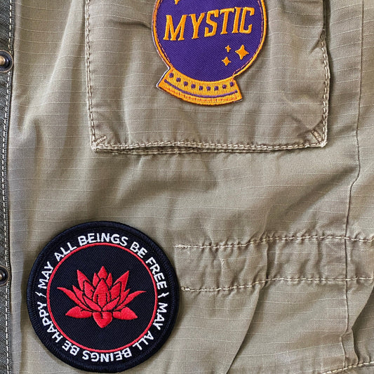 Two patches on a jacket: one with 'Mystic' text and a purple circle, the other with a 3" round patch with a red lotus flower and the text, may all beings be free may all beings be happy.