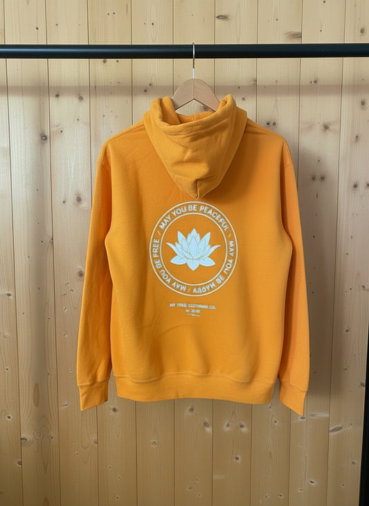 Backside of a gold hoodie with a white round lotus that reads, may you be peaceful-may you be happy- may you be free.