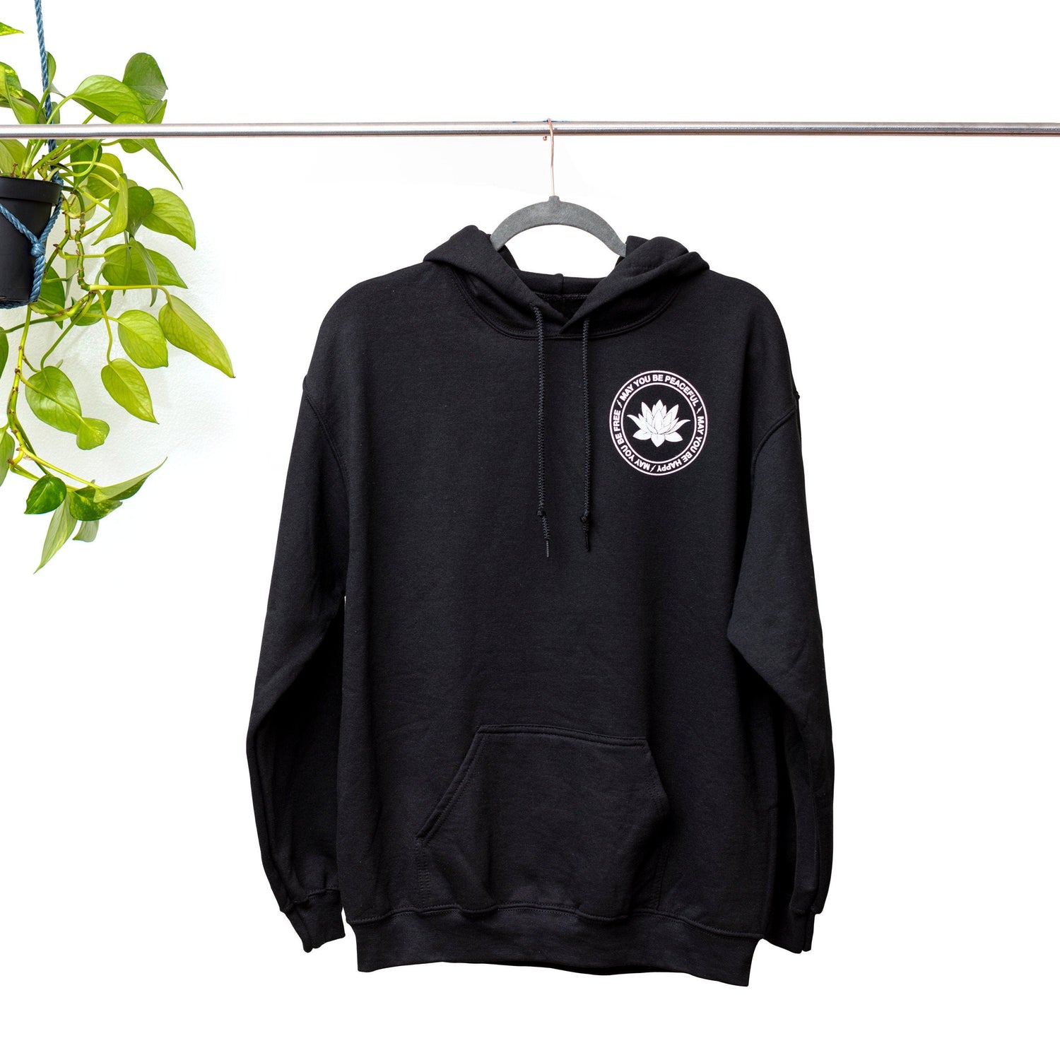 Black Hooded sweatshirt with a white lotus over the left side with the words, May All Beings Be Happy-May All Beings Be Free. The back has the same art lotus design in a larger size.