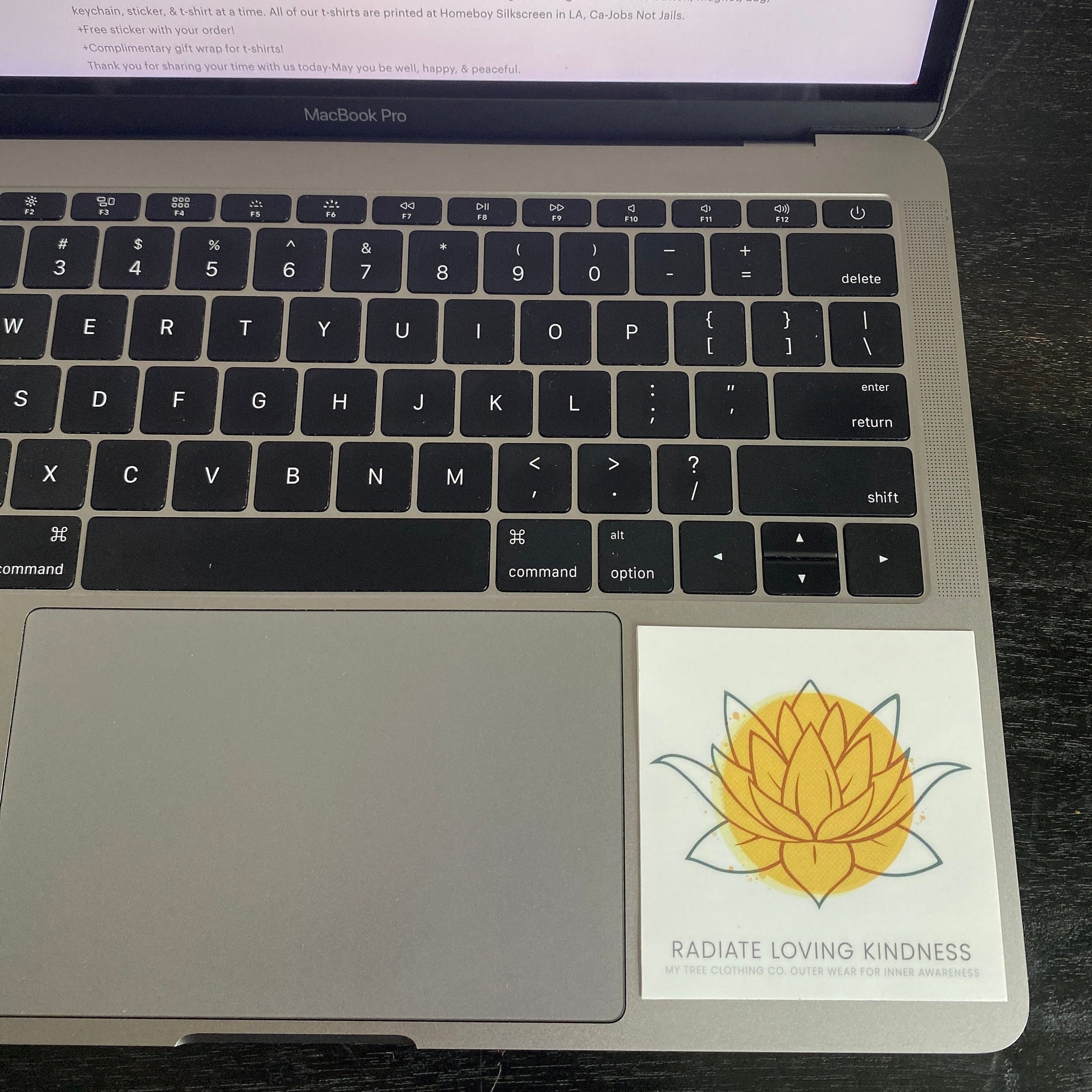Laptop with a sticker of a yellow flower 'Radiate Loving Kindness' 3" square sticker.