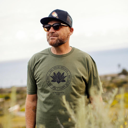 Man wearing a green t-shirt with a lotus and the text, may you be peaceful, may you be happy, may you be free.