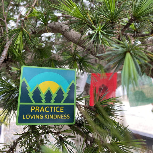 3" square ultra thin magnet with trees and a sunrise and the text 'Practice Loving Kindness' on a pine tree branch with Tibetan prayer flags in the background.