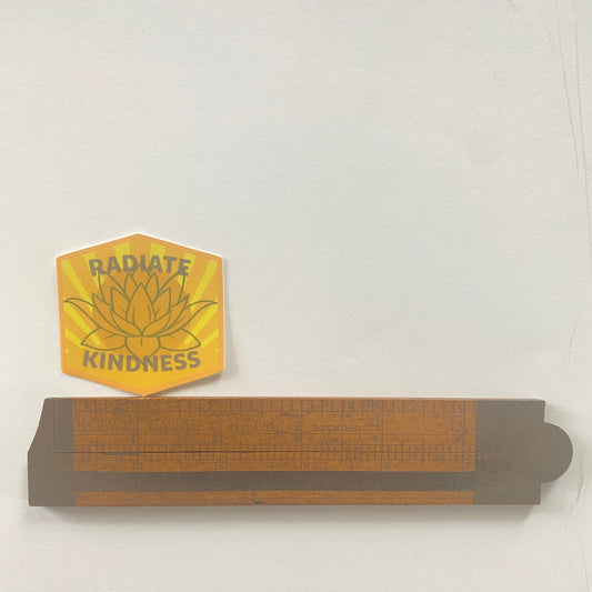 Wooden ruler with a yellow lotus flower design and 'Radiate Kindness' text on a white background