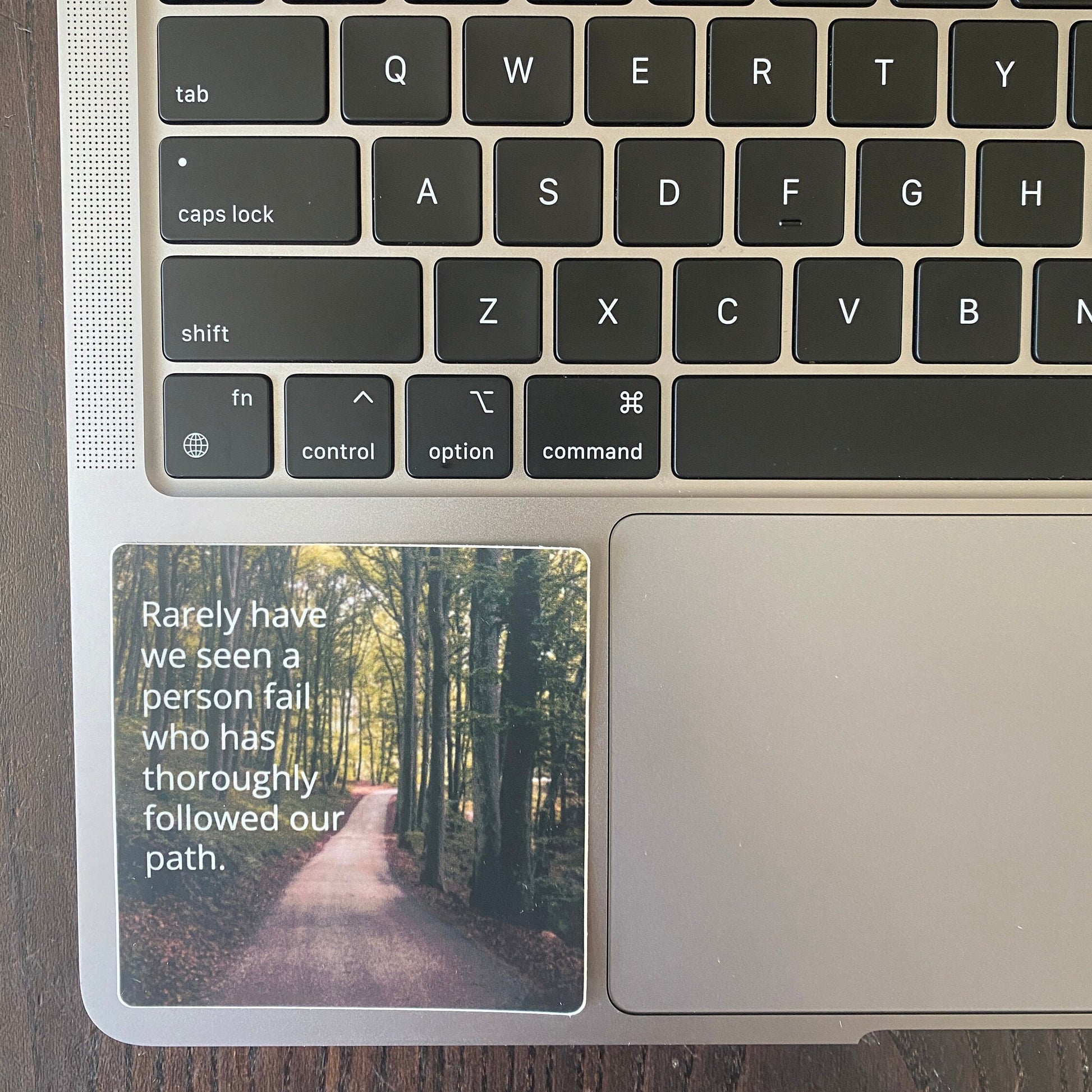 Laptop keyboard with a 3" square 12 step recovery sticker with a quote from the big book of alcoholics anonymous, 'rarely have we seen a person fail who has thoroughly followed our path.'
