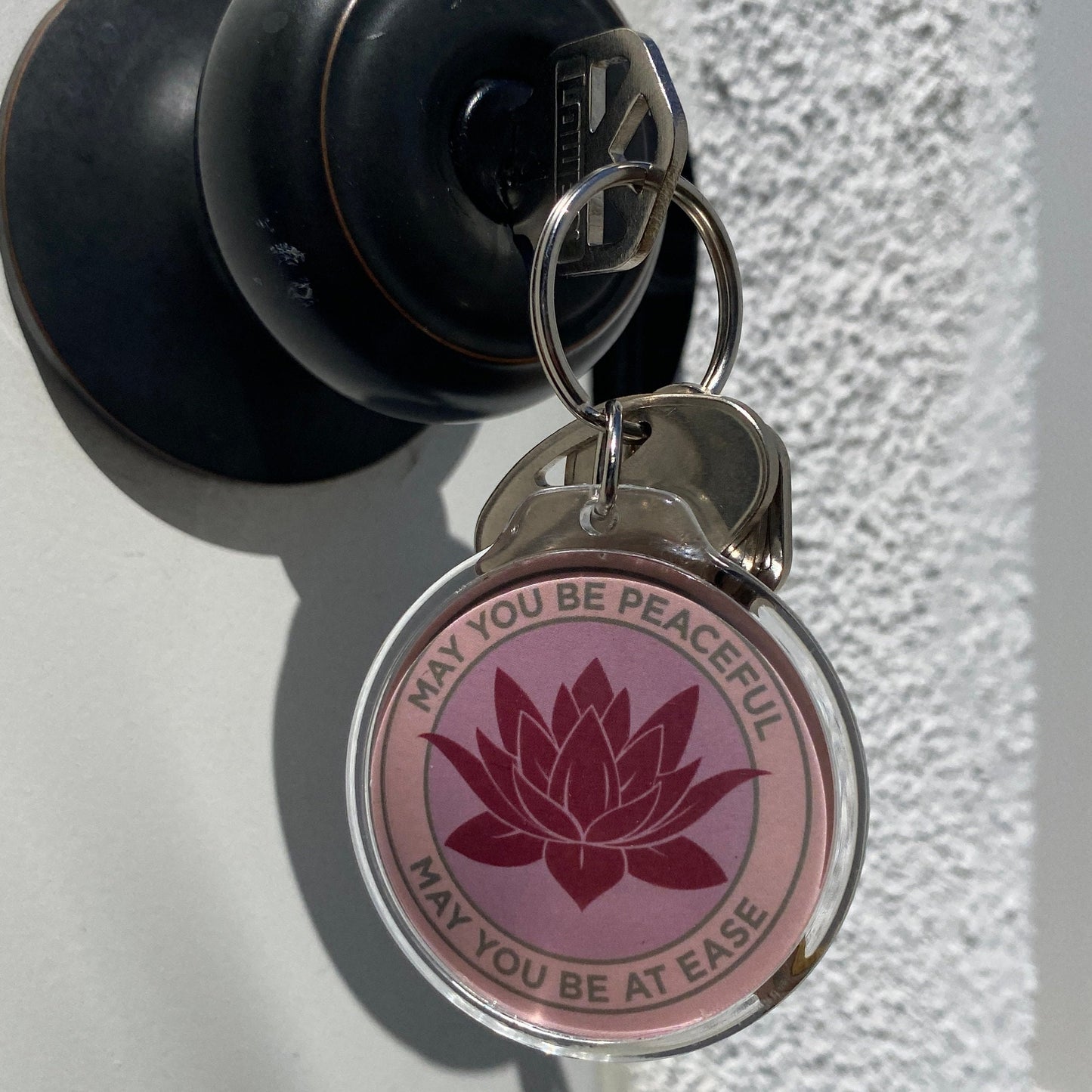 Keychain with pink lotus design and text on a textured surface