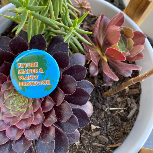 Button with 'Future Leader & Planet Protector' text on a potted plant
