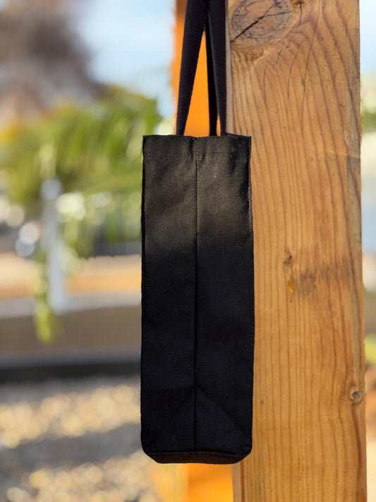 Side view of black tote bag hanging on a wooden post outdoors.