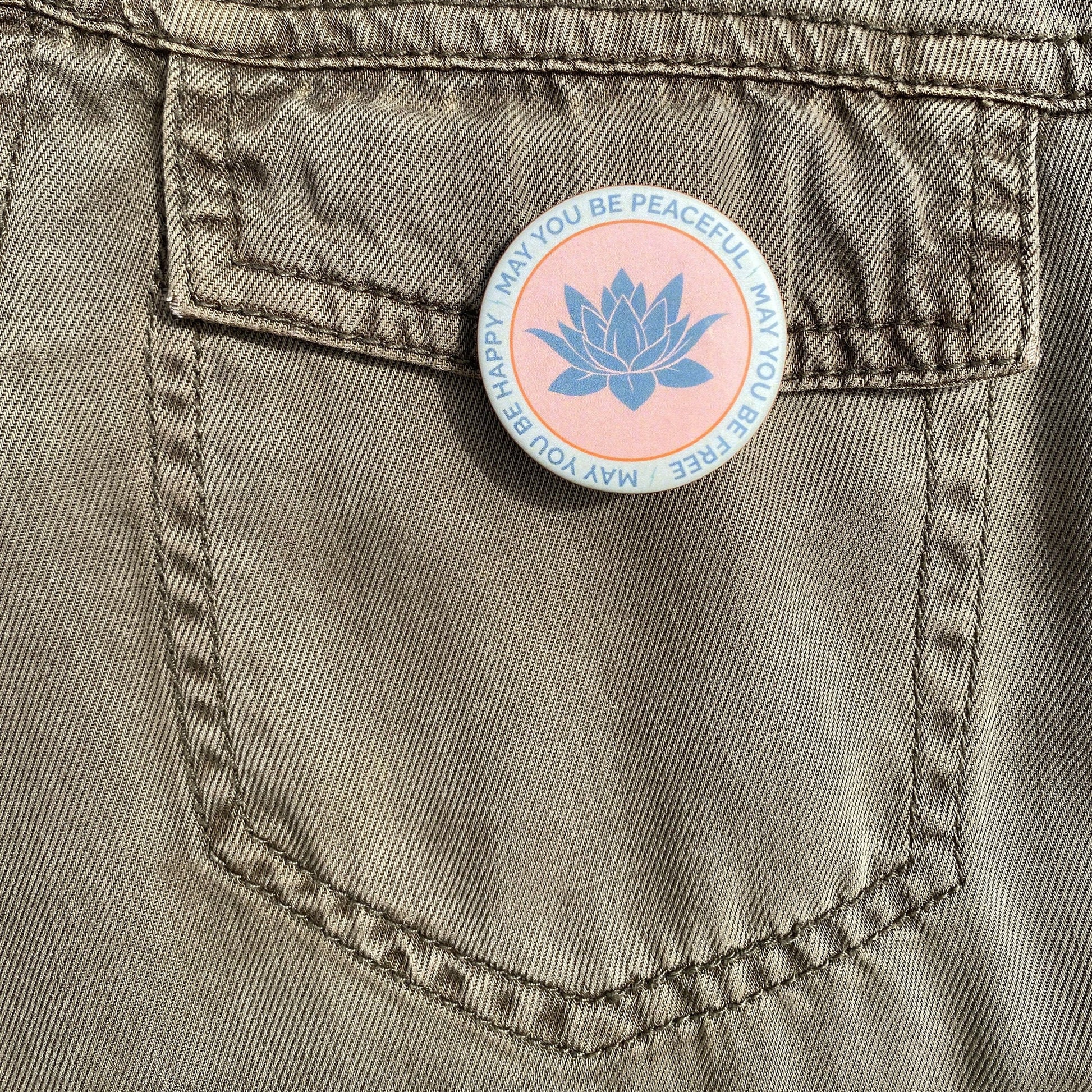 Button with a blue lotus design on a pocket of a brown denim jacket