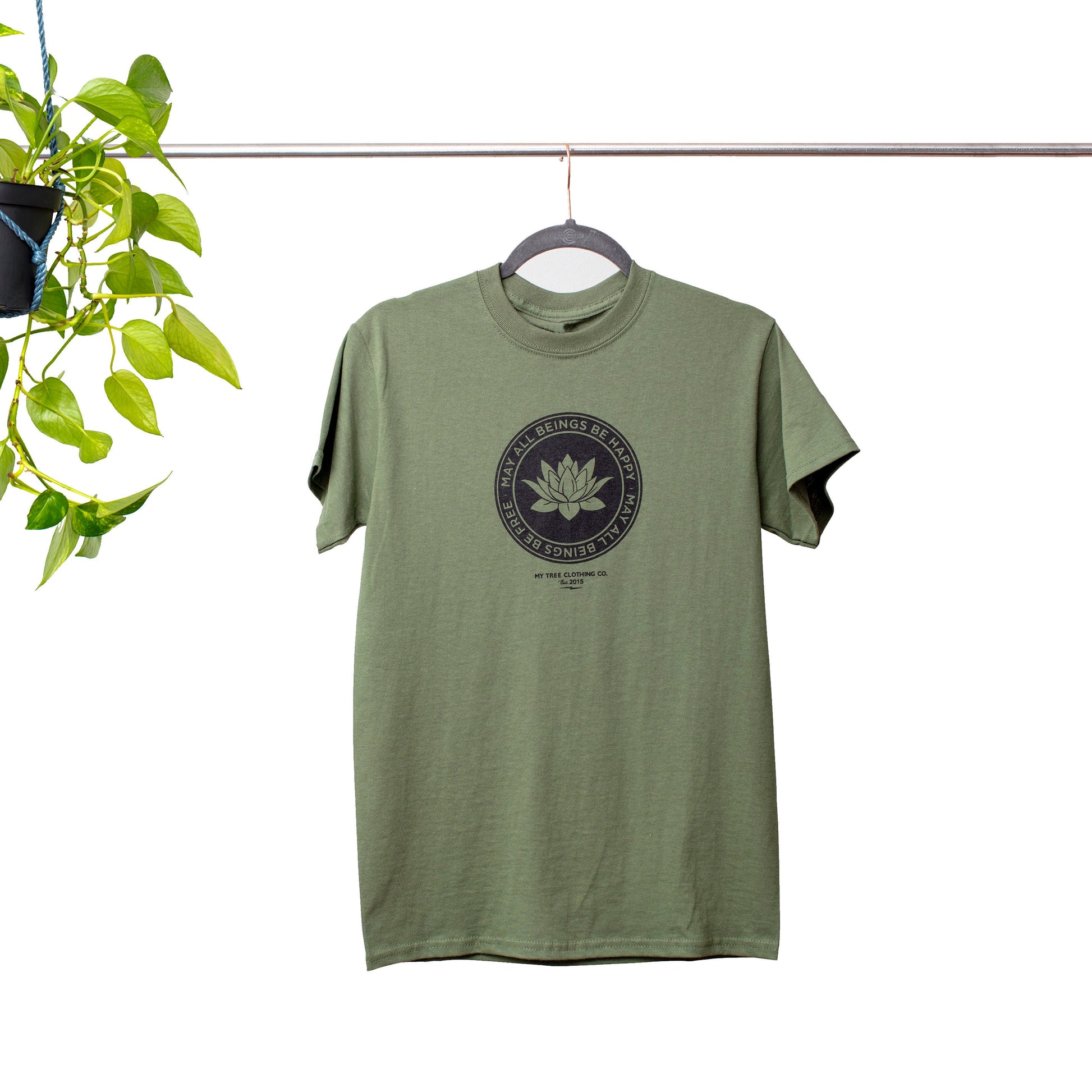 Green Buddhist lotus shirt with the text, May All Beings Be Happy May All Beings Be Free, on a hanger against a white background.