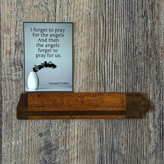 Leonard Cohen quote, 'I forget to pray for the angels and then the angels forget to pray for us.' It's being measured by an antique ruler.