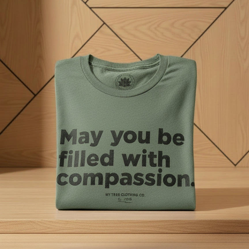 Folded green-shirt with text, may you be filled with compassion.