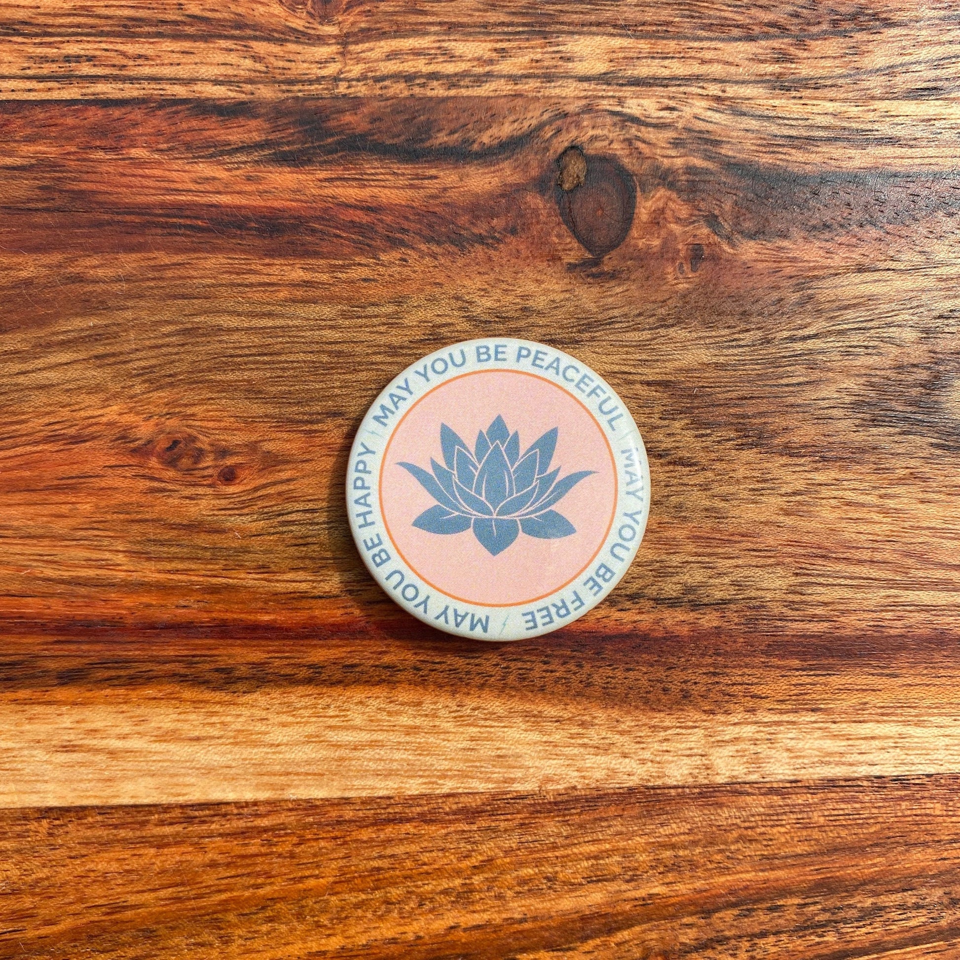 Round button with lotus flower design and text on a wooden surface
