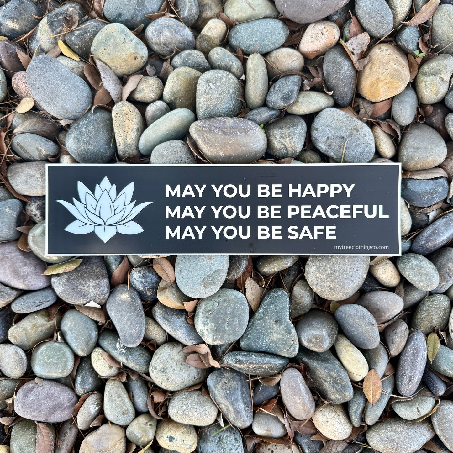 Buddhist phrase, MAY YOU BE HAPPY-MAY YOU BE PEACEFUL-MAY YOU BE SAFE bumper sticker with a white lotus on pebbles.