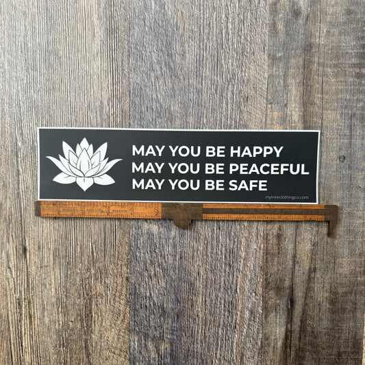 Buddhist phrase, MAY YOU BE HAPPY-MAY YOU BE PEACEFUL-MAY YOU BE SAFE bumper sticker with a white lotus on a wooden surface