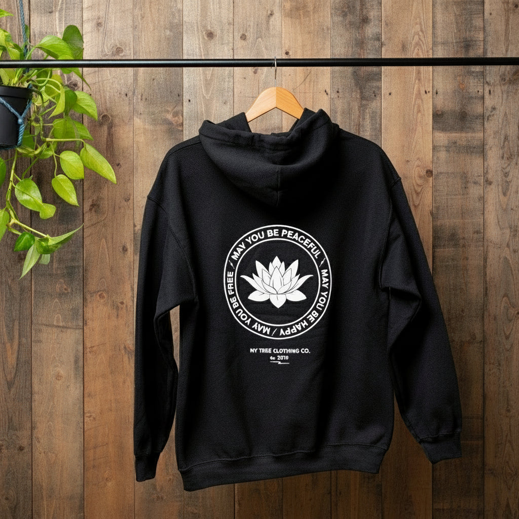 Backside view of black hoodie with a white lotus and the mettā prayer, 'may you be peaceful may you be happy may you be free.'