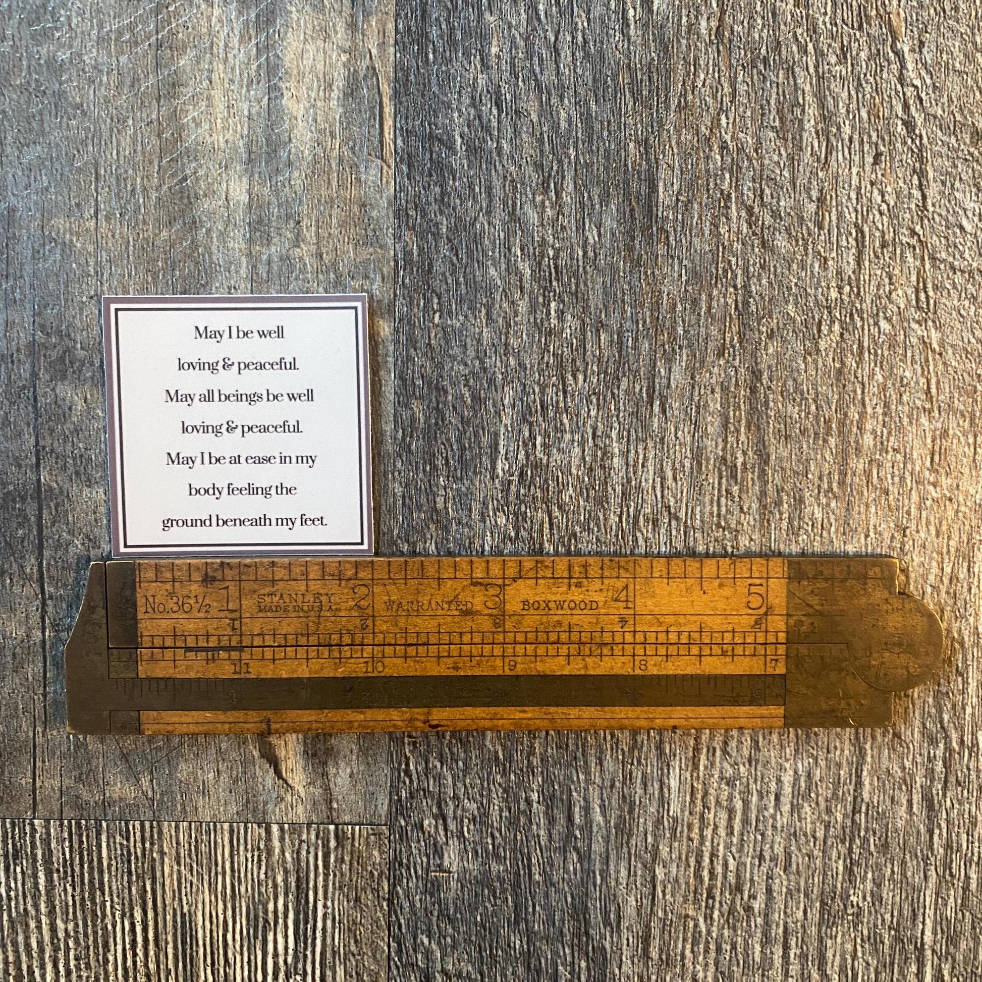 2" square Buddhist prayer being measured by an antique wooden ruler.