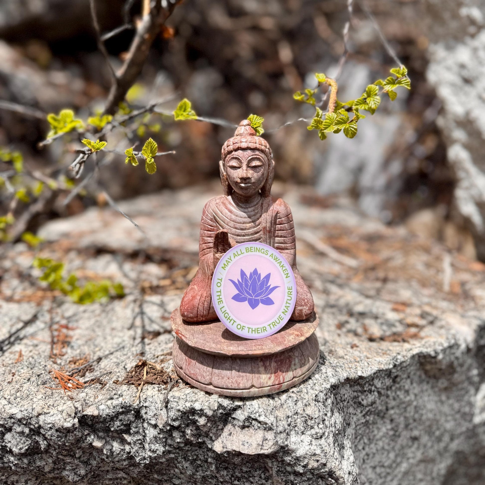 Buddha statue with a 3" round sticker with a purple lotus flower design and the text, may all beings awaken to the light of their true nature.