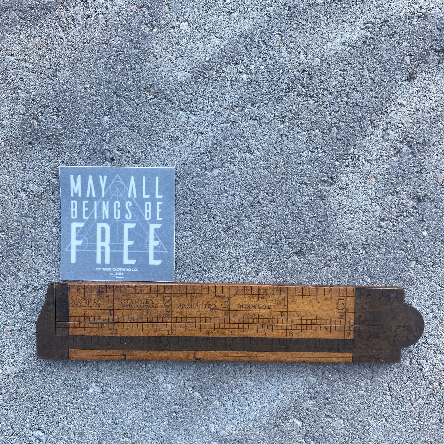 2" square grey sticker with 'May all beings be free' text with sacred geometry design.