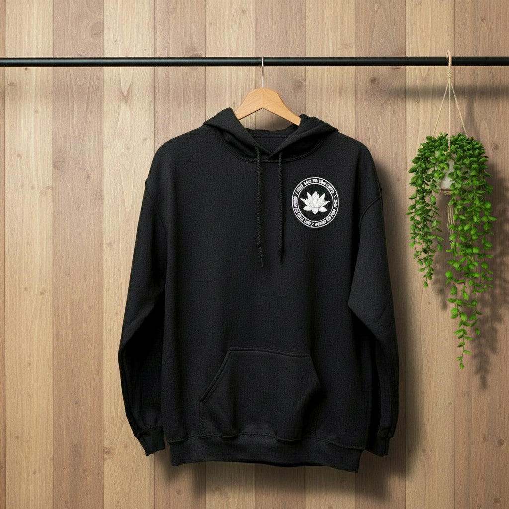 Black hoodie with a white lotus and the mettā prayer, 'may you be peaceful may you be happy may you be free.'